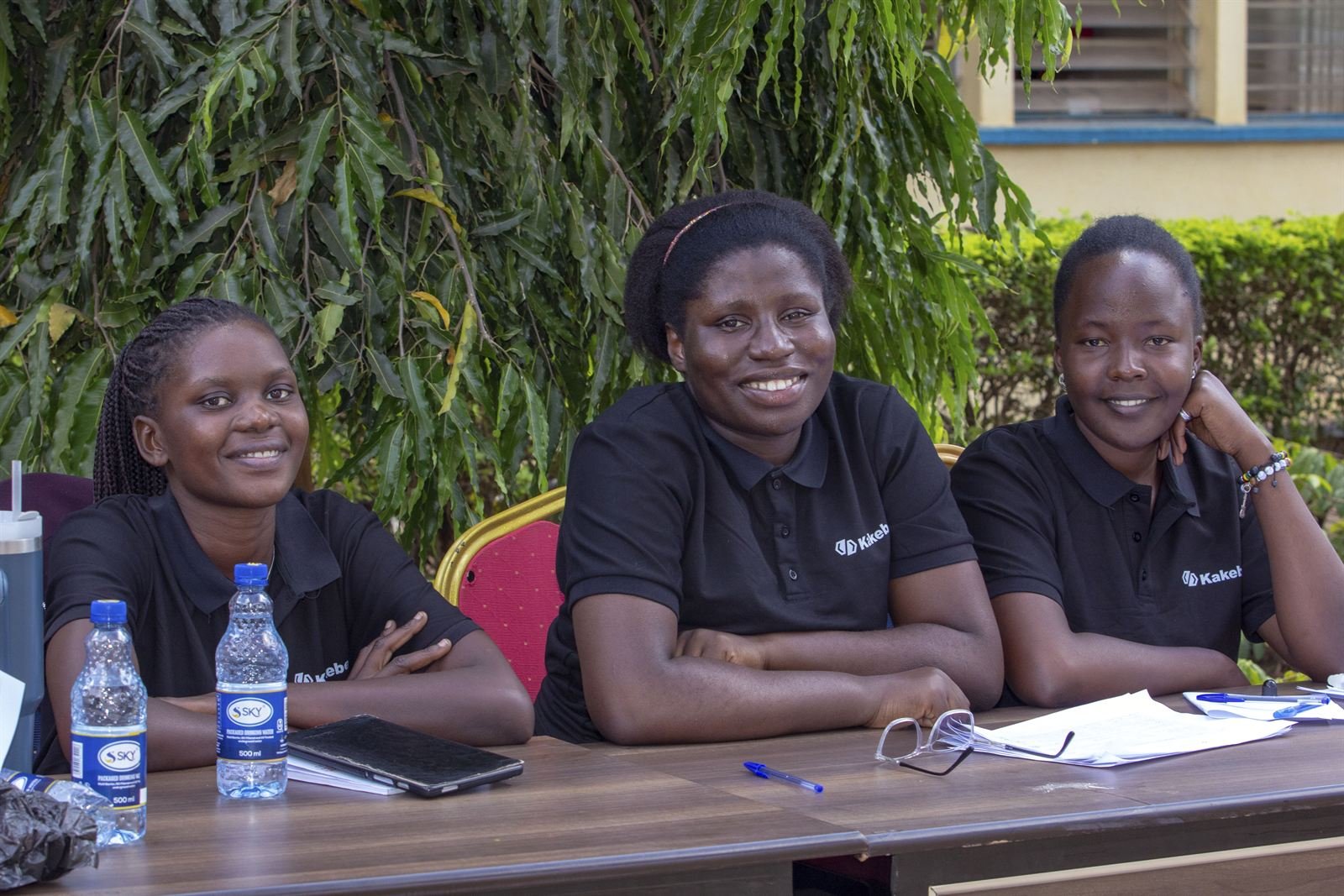 Three Kakebe team members smiling at a registration desk