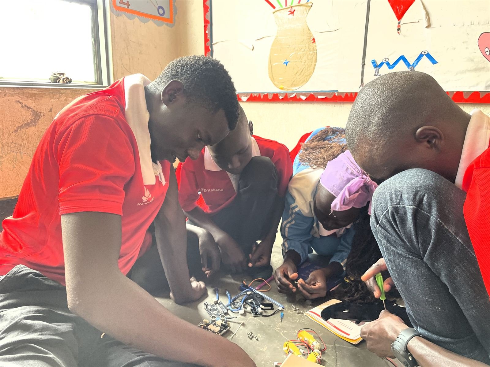 Young people assembling a robot during a hands-on Kakebe Tech Camp robotics session